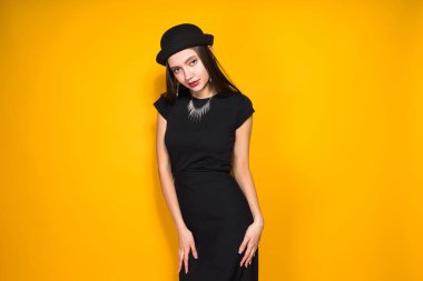 güzel çekici model kız moda siyah şapka ve siyah elbise sarı arka plan üzerinde poz