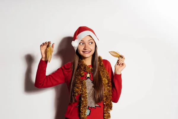 Feliz joven en rojo ropa de Navidad está cogido de la mano con juguetes de Navidad —  Fotos de Stock