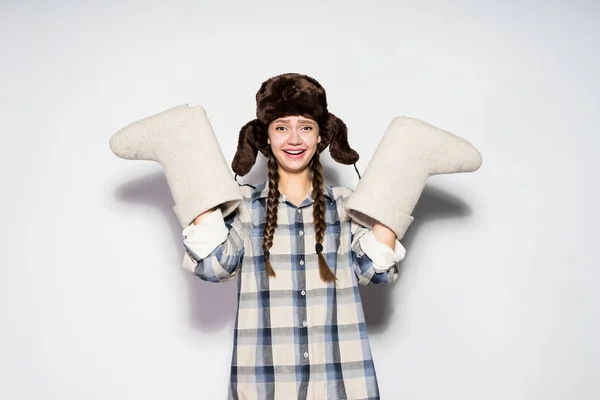 Gelukkig jong Russisch meisje in een muts met oorkleppen houdt warme winter voelde laarzen — Stockfoto