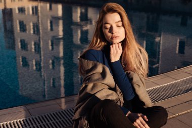 Mavi kazak açık havada güneş, gözleri kapalı poz içinde güzel genç sarışın kız