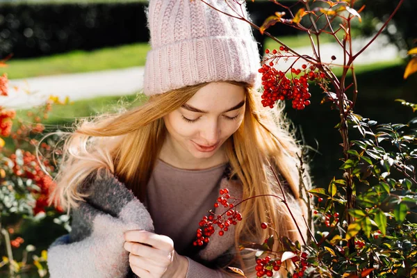Söt ung blond tjej i en rosa hatt promenader i trädgården, njuta av varmt väder och sol — Stockfoto