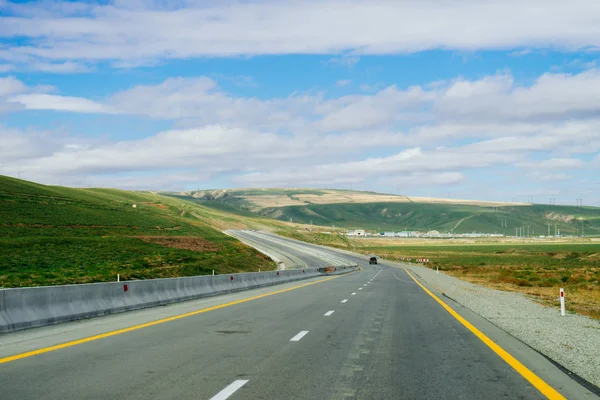 Highway in the mountains, endless green fields and blue sky — Stock Photo, Image