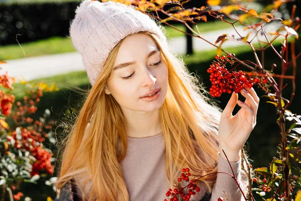 Carino giovane ragazza bionda in un cappello rosa passeggiando in giardino e godendo la natura primaverile e il sole — Foto Stock