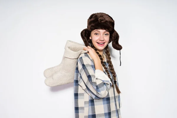 Gelukkig mooi Russisch meisje in een warme muts met oorkleppen houdt winter laarzen — Stockfoto