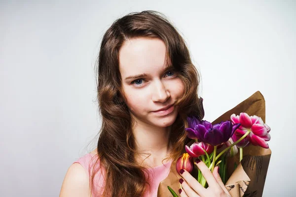 Atractiva joven sosteniendo un ramo de flores, celebrando el día mundial de la mujer, 8 de marzo — Foto de Stock