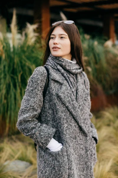 Mignonne jeune fille dans un manteau gris à la mode marchant dans les rues de la ville, style de rue — Photo