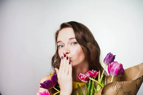 Joven feliz sosteniendo un ramo de flores en sus manos, enviando un beso aéreo, celebrando el día mundial de la mujer — Foto de Stock