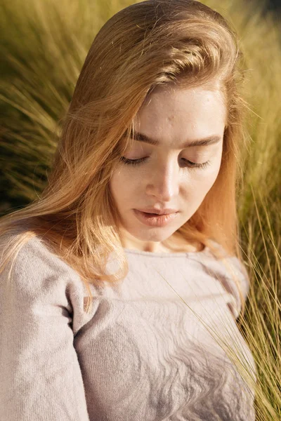 Giovane bella ragazza bionda in posa in un campo al sole, caldo clima primaverile — Foto Stock