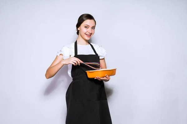 Красива молода жінка шеф-кухаря в чорному фартусі робить смачний пиріг — стокове фото