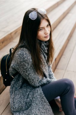 Şehrin etrafında bir yürüyüş sonra merdivenlerden bir genç esmer şehir kız gri bir ceket ve gözlük oturur