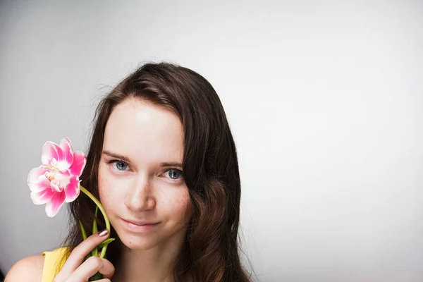 Junges schönes Mädchen hält eine duftende rosa Blume in der Hand und feiert den Muttertag — Stockfoto