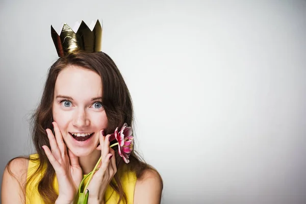 Menina feliz em um vestido amarelo, em sua cabeça uma coroa de ouro se alegra em um feriado, dia de uma mulher mundial — Fotografia de Stock