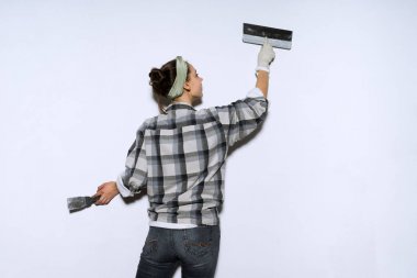 Genç bir kız bir ekose gömlek satırlarındaki yeni eviyle, duvarlarda onarım yapar