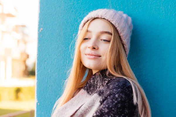 美しい笑みを浮かべて少女金髪ピンクの帽子を背景に青い壁、ポージングで公園を歩いて — ストック写真