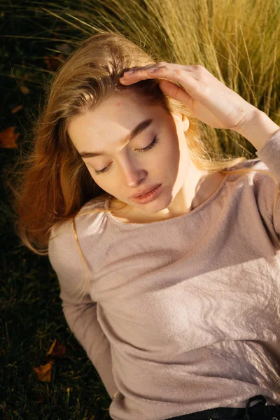 Jovem mulher loira atraente posando em um campo ao sol — Fotografia de Stock