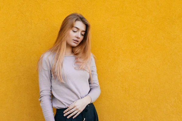 Красива молода блондинка модель дівчина позує на жовтому фоні стіни, вуличному стилі та моді — стокове фото