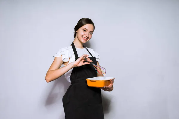 Усміхнена молода дівчина готує в чорній сукні готує смачну страву — стокове фото