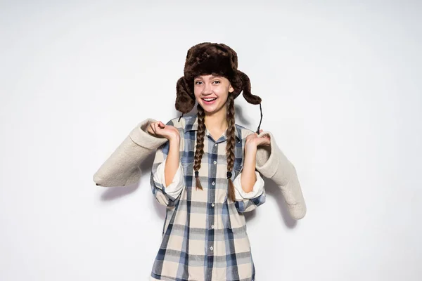 Feliz joven rusa en sombrero caliente sostiene botas de fieltro gris en las manos, sonriendo — Foto de Stock