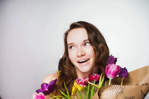 Lyckligt leende ung flicka håller en stor bukett blommor, firar den internationella kvinnodagen, 8 mars — Stockfoto