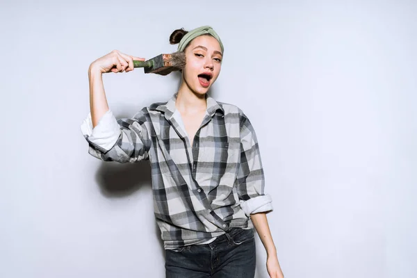 Funny young girl in plaid shirt holding brush for painting walls — Stock Photo, Image
