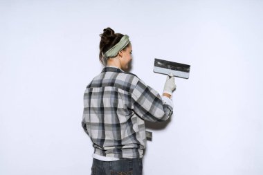 bir duvar bir spatula ile tesviye, tamir ekose gömlekli çalışkan genç kadın