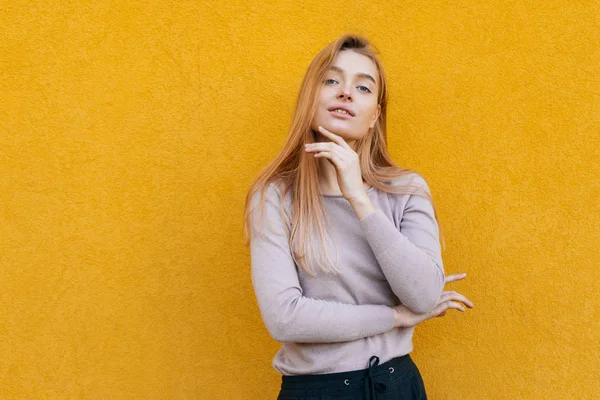 Hermosa joven rubia en ropa de moda posando contra una pared amarilla, estilo de calle — Foto de Stock