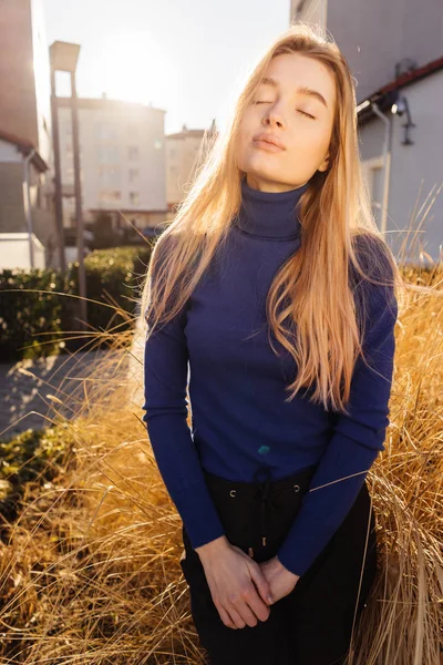 Bella ragazza modello bionda attraente in maglione blu passeggiando per le strade della città, godendo del bel tempo e del sole — Foto Stock