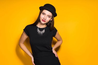 emin çekici model kız şık siyah şapka ve Sarı zemin üzerine poz elbise
