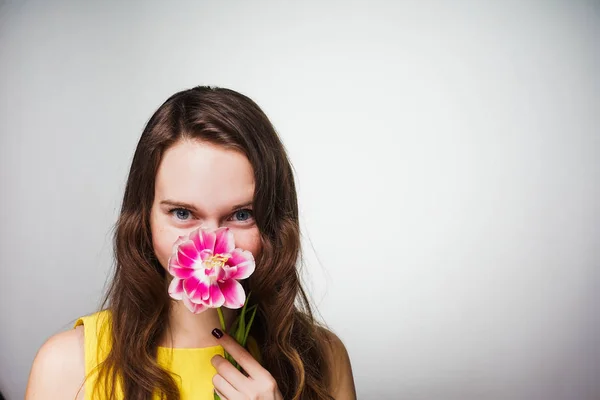 Lustiges junges Mädchen schnuppert an einer rosa Blume, feiert den Weltfrauentag — Stockfoto