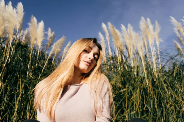 Attraente bella ragazza modello bionda in posa in un campo verde, al sole, sotto un cielo blu — Foto Stock