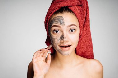 bir havlu kafasındaki sürpriz genç kızla yararlı bir maske yarım yüz, spa uygulamaları zevk uygulanan