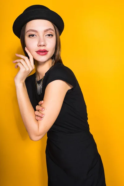 Atrakcyjna młoda dziewczyna w czarnej sukni i kapelusz, pozowanie, demonstrując kosztowna biżuteria — Zdjęcie stockowe