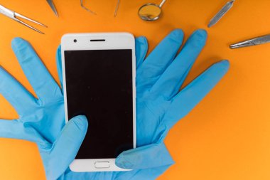 turuncu bir arka plan üzerinde bir smartphone ise mavi Medikal Ürünler, diş aletleri