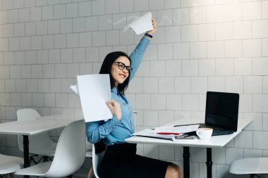mutlu güzel kız freelancer gözlük ve mavi gömlek ile gerçekleştirilmiş tüm işleri, belgeleri elinde tutan