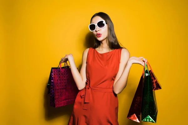 一个可爱的年轻女孩穿着红色的连衣裙和太阳镜去购物在星期五 — 图库照片