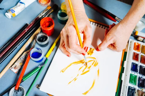 Femme peintre peint sur papier blanc avec peinture jaune et pinceau — Photo