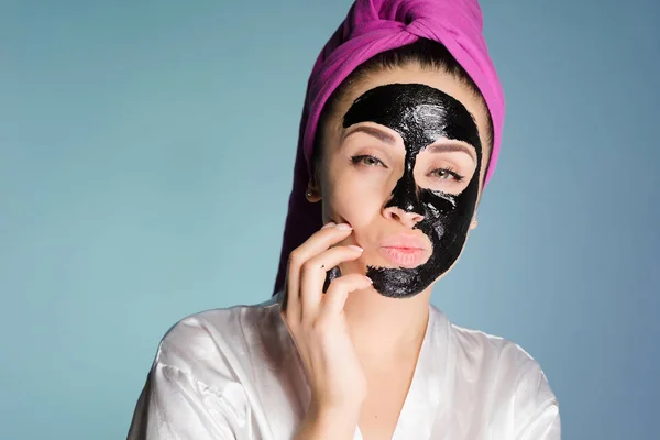 Rolig ung flicka med rosa handduk på huvudet tillämpas en svart mask mot akne — Stockfoto