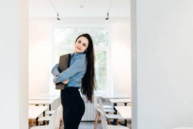 ofiste duran ve bir dizüstü bilgisayar elinde tutan bir iş kadını