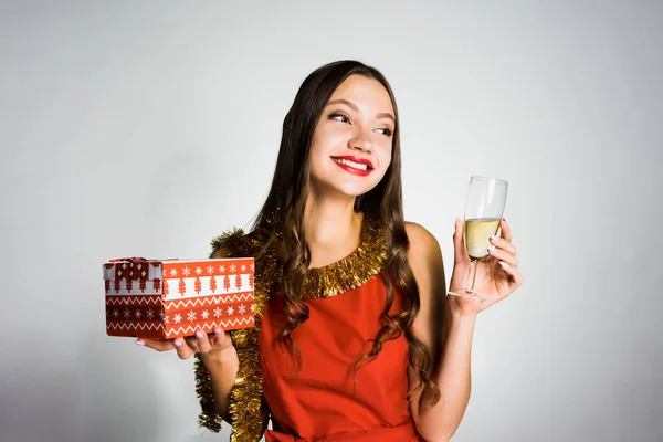 Happy woman holding a gift and a glass of champagne in her hands — Stock Photo, Image