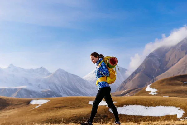 Turista mujer caminando sobre el telón de fondo de las montañas en un día soleado —  Fotos de Stock