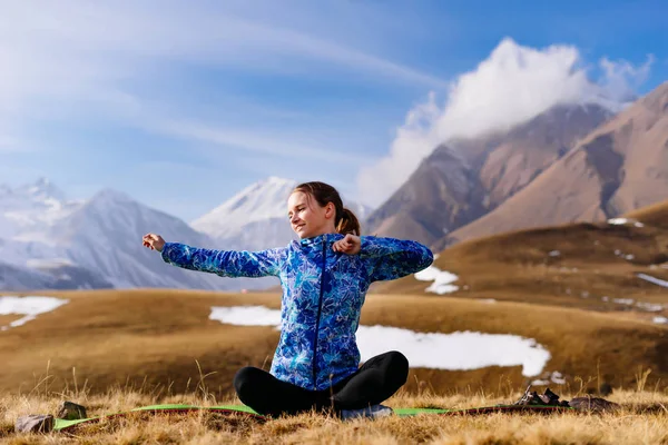 Kadın turist halının üzerinde oturan ve arka planda dağların egzersizleri yapıyor — Stok fotoğraf