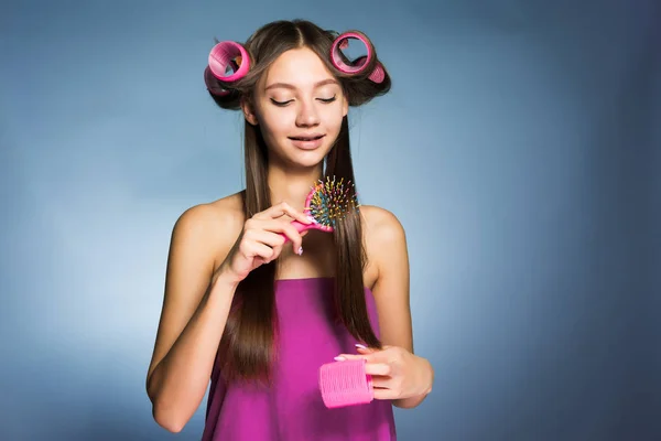 Uma mulher com encrespadores no cabelo penteia o cabelo — Fotografia de Stock