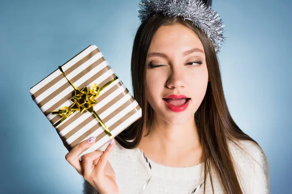 Eine Frau auf blauem Hintergrund bereitet sich darauf vor, ihr Neujahrsgeschenk zu öffnen — Stockfoto
