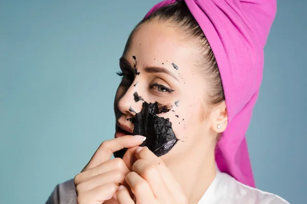 Une femme enlève le masque nettoyant de la peau du visage — Photo