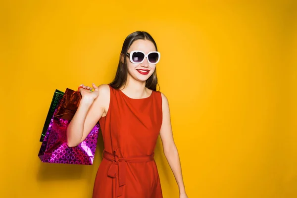 Женщина на жёлтом фоне держит покупки в руках — стоковое фото