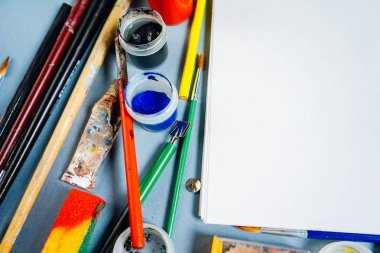 mavi bir arka plan üzerinde orada boyalar, fırçalar ve bir beyaz kağıt