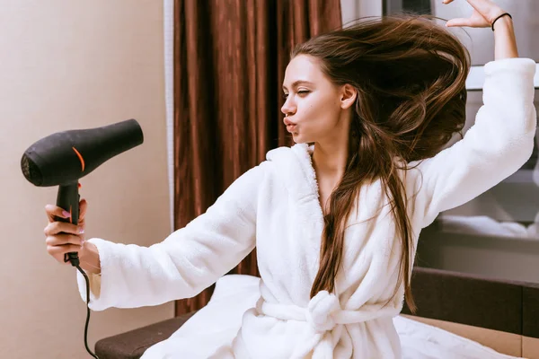 Γυναίκα κάθεται στο κρεβάτι και στεγνώνει τα μαλλιά της — Φωτογραφία Αρχείου