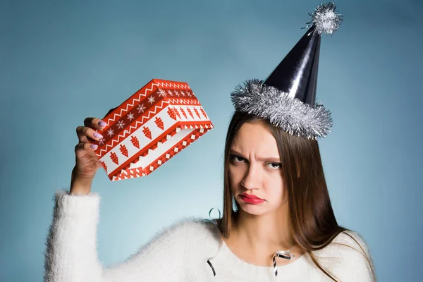 Een gefrustreerde vrouw in een feestelijke hoed houdt een lege geschenkverpakking — Stockfoto