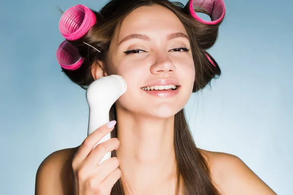 Femme sur un fond bleu utilise une brosse pour le nettoyage en profondeur — Photo