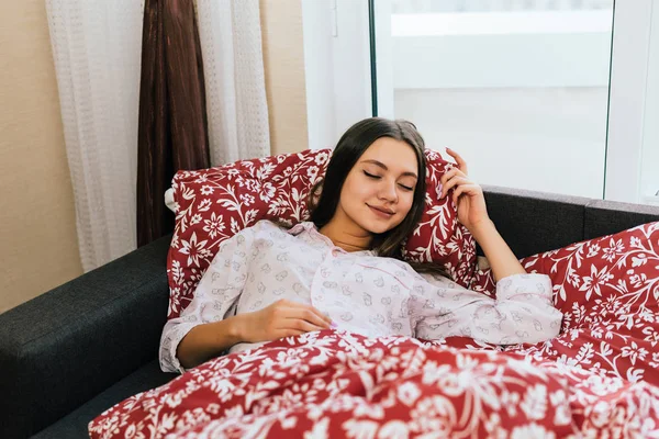 Woman lies in bed under a blanket smiling — Stock Photo, Image